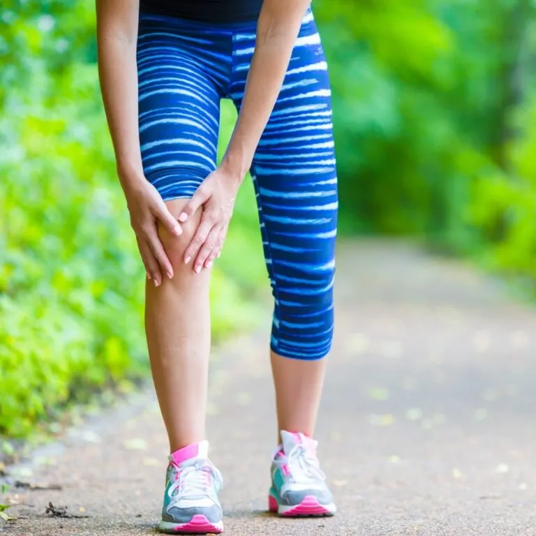Female runner clutching her knee with a sports-related joint injury