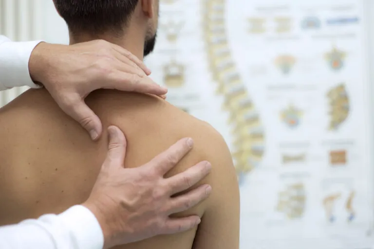 Person with their hand on their shoulder showing shoulder-blade pain