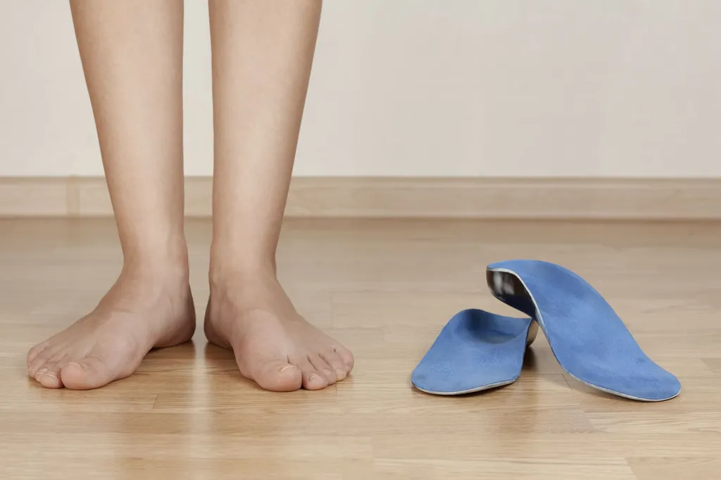 Pair of custom orthotic insoles next to a foot mould on a clinic table